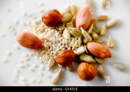 still life of mix of peanuts, sunflower seeds & sesame seeds against a white background, close up top shot Stock Photo