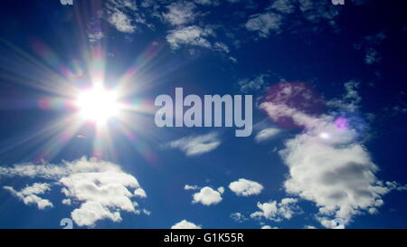 Desert sun rays streaking in blue sky with patchy clouds Stock Photo