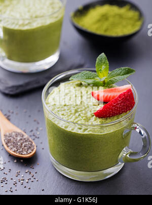 Matcha green tea chia seed pudding, dessert with fresh mint and strawberry on a black slate background Healthy breakfast Stock Photo