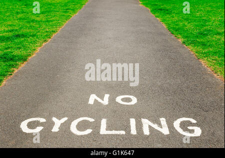 Closeup of “No Cycling” warning written with white paint on tarmac pavement with copy space Stock Photo