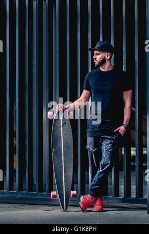 Full body portrait of bearded stylish man with longboard Stock Photo