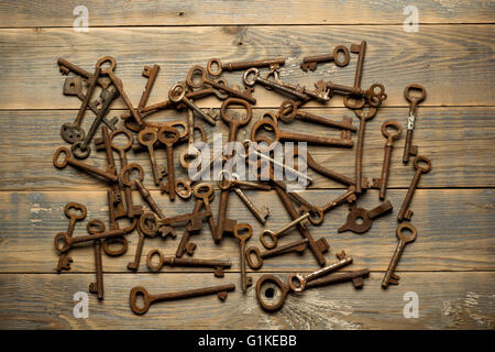 Many old keys on a well used wooden desk Stock Photo