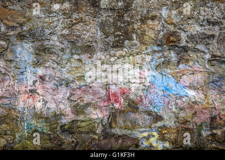 Grungy stone wall with paint and algae. Stock Photo