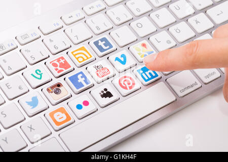 BELCHATOW, POLAND - AUGUST 31, 2014: Male hand pointing on key with a social media logotype printed and placed on keyboard. Stock Photo