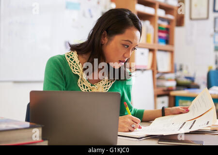 Female Asian teacher at her desk marking students’ work Stock Photo - Alamy