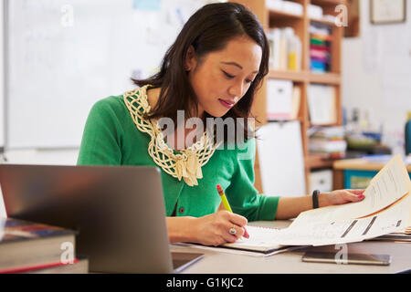 Female Asian teacher at her desk marking students’ work Stock Photo - Alamy
