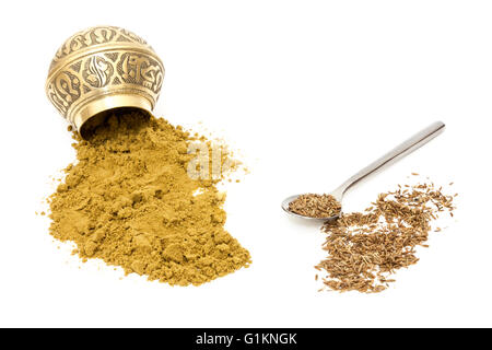 Ground cumin powder tipped from a spice bowl and spoon with whole cumin or jeera seeds. Isolated on a white background Stock Photo