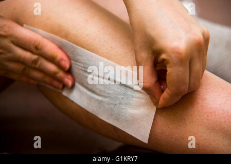 Amateur woman getting legs waxed for hair removal in home Stock Photo