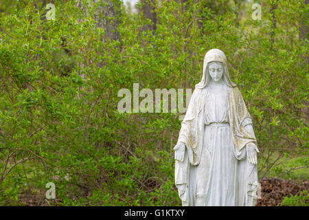 stone statue of Mary in prayer with open palms facing forward Stock Photo