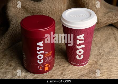 A tin of roasted and ground Costa coffee and a takeaway coffee cup on a Hessian background. Stock Photo