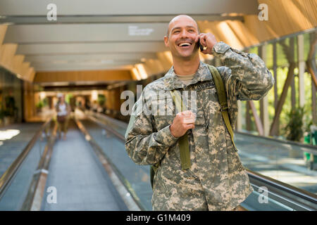 Caucasian soldier talking on cell phone in airport Stock Photo