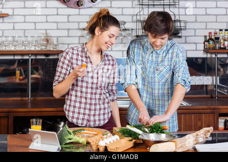 Beautiful young couple standing and cooking together on the kitchen Stock Photo