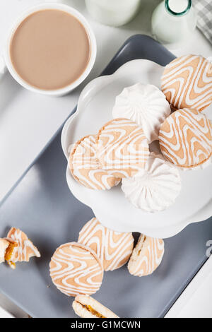 Cookies on white and gray plate with cups of coffee and bottles of milk on white shutters background, top view Stock Photo