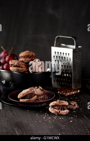 Italian maroni cookies on the plate and bowl with grapes, cloth, notebook on dark old wooden background Stock Photo