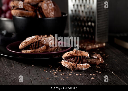 Italian maroni cookies on the plate and bowl with grapes, cloth, notebook on dark old wooden background Stock Photo