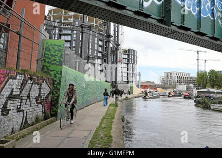 Cyclist riding on towpath along Regents Canal past new Gasholders Apartments in Kings Cross London UK  KATHY DEWITT Stock Photo