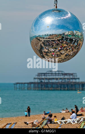 Brighton beach reflected in a mirror ball hanging in one of the seafront cafés. The remains of the West pier can be seen behind. Stock Photo