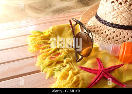Beach articles on a table wooden slats and sea background with sunbeam. Horizontal composition. Elevated view. Stock Photo
