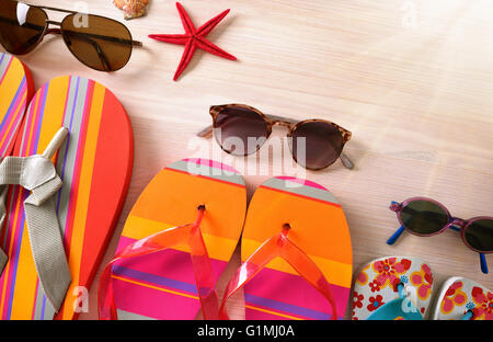 Sunglasses and flip-flops family beach ready to go to the beach on a wooden table and sunbeam. Horizontal composition, Top view Stock Photo
