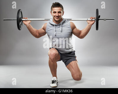 Man doing lunges with barbell on back in the studio Stock Photo