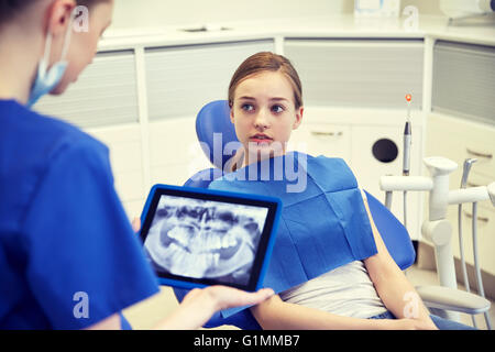 dentist showing x-ray on tablet pc to patient girl Stock Photo