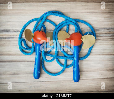 New blue skipping rope on the wooden background. Leisure activity. Healthy lifestyle. Individual sport. Tangled rope. Stock Photo