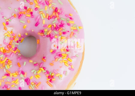 A large donut with pink icing and sprinkles showing its hole on an isolated white background. Stock Photo