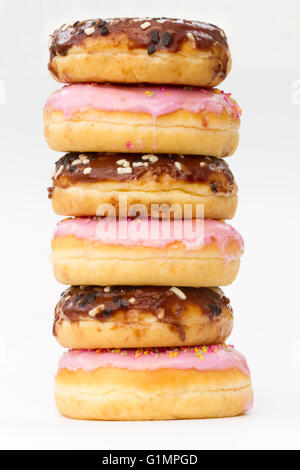 A stack of chocolate and pink iced doughnuts with sprinkles on an isolated white background. Stock Photo