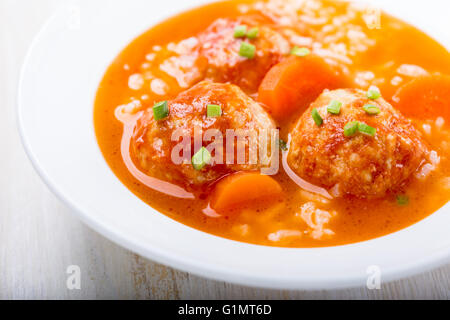 Homemade chicken meatball soup with rice in white plate, quick, hot, and delicious winter warmer meal Stock Photo