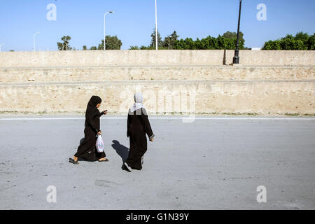 Two Muslim women passing by the walls surrounding the  Great Mosque of Kairouan in the street of Kairouan, Tunisia. Stock Photo