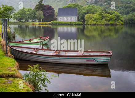 Gougane Barra, County Cork, Republic of Ireland.  Eire.  Looking across rowing boats moored at the lake shore with the Hermitage Stock Photo