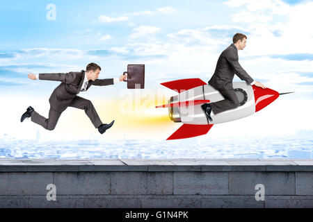 Running businessman following man flying on rocket Stock Photo