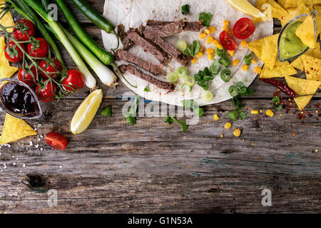 Food background with nachos chips and ingredients for making tartilla. Onion, tomatoes, chili peppers, beef, tortillas and corn Stock Photo