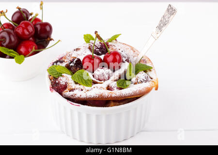 French clafoutis with cherry in ceramic ramekins on white wooden table Stock Photo