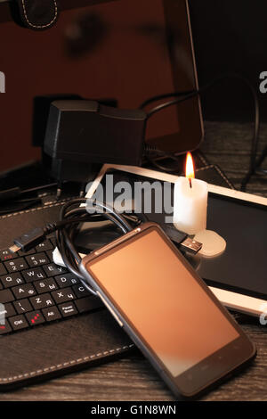 Blackout concept. Lighting candle on set of modern electronic gadgets Stock Photo