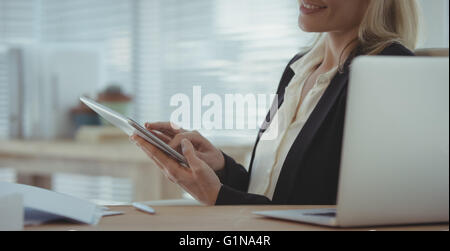 Businesswoman is smiling and using tablet and computer Stock Photo