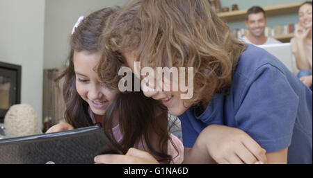 Children playing with tablet while parents using computer Stock Photo