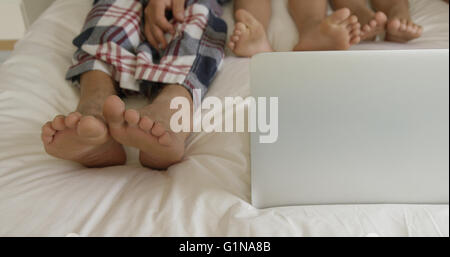 Family using laptop on bed Stock Photo
