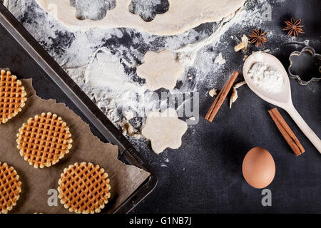 Cookie ingredients like eggs, flour, cinnamon, anise, rolling pin, paper on blackboard from the top Stock Photo