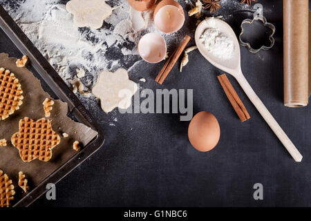 Waffles  ingredients like eggs, flour, cinnamon, anise, rolling pin, paper on blackboard from the top Stock Photo
