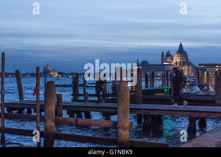 Basilica Santa Maria della Salute and Chiesa di  at night seen from Riva degli Schiavoni vaporetto stop Stock Photo