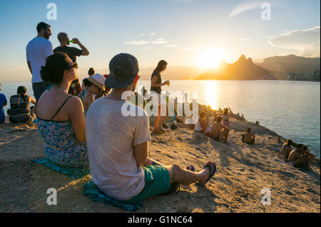 RIO DE JANEIRO - FEBRUARY 26, 2016: Crowds of people gather to watch the sunset on the rocks at Arpoador, a popular activity. Stock Photo