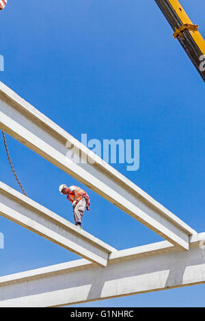 Height worker is high up on concrete frame without proper safety equipment. Stock Photo