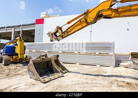Excavator is replacing tool for bucket at construction site. Stock Photo
