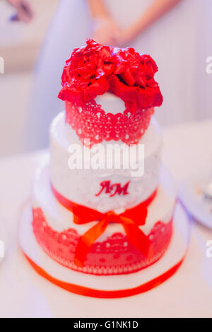 Beautyfully decorated white wedding cake with red flowers on top Stock Photo