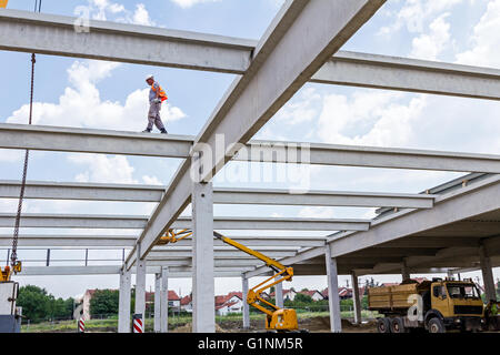 Construction worker is walking over on building concrete beam without proper safety equipment. Stock Photo