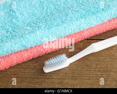The blue and pink towel with white toothbrush on wooden plank background. Stock Photo