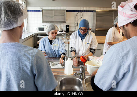 International class during baking a cake in the school kitchen. The trainees wash the kitchen utensils. Stock Photo