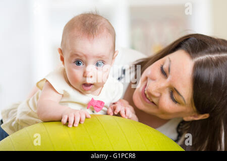 Mother with little child doing exercises with gymnastic ball. Concept of caring for the baby's health. Stock Photo