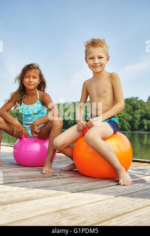 Two children playing with a spacehooper at a lake in summer Stock Photo